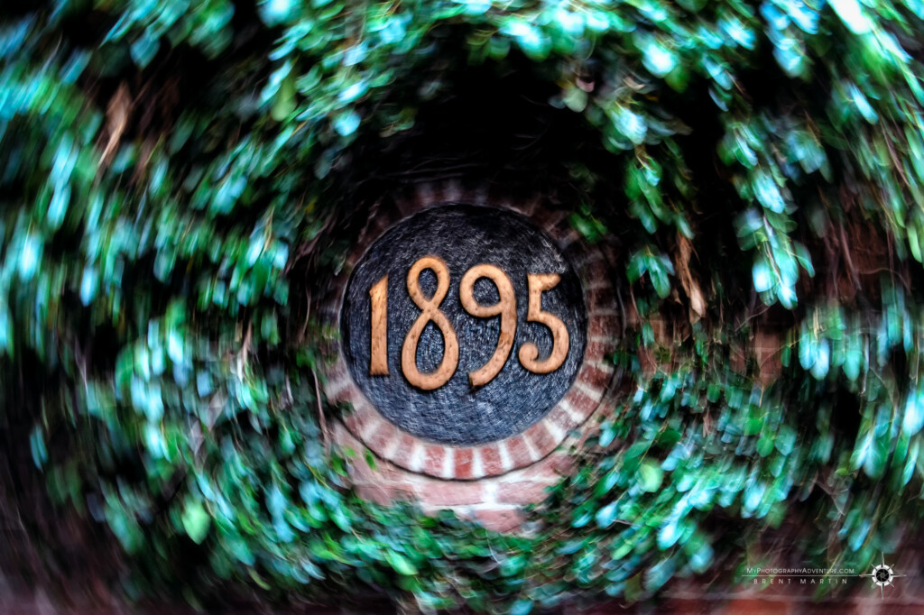 Intentional camera movement rotational blur of brick address surrounded by ivy.